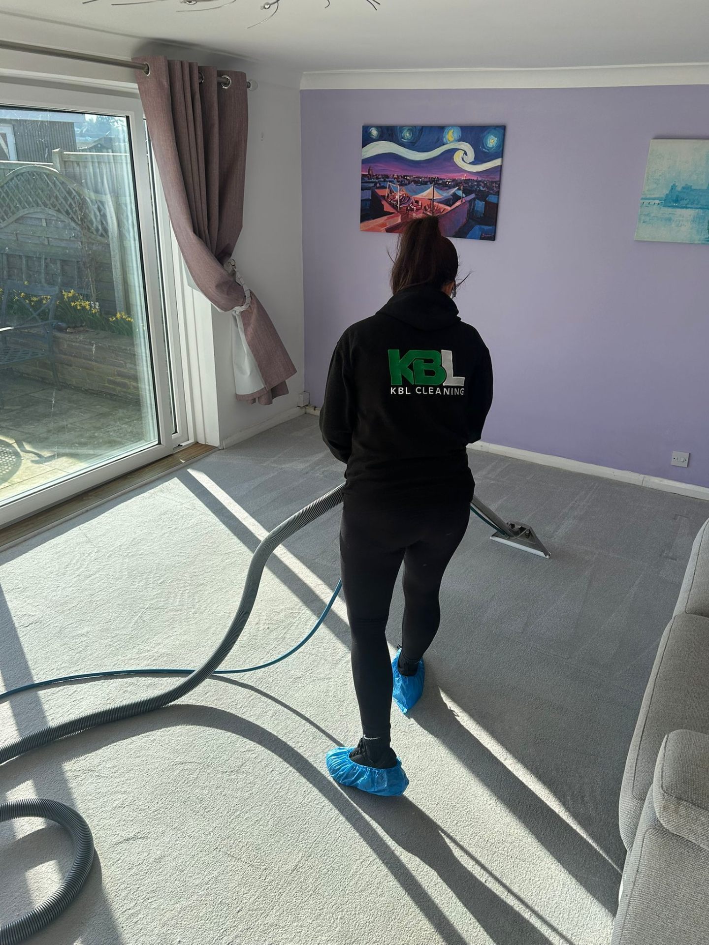 KBL Cleaning technician professionally steam cleaning a carpet in a customer's living room