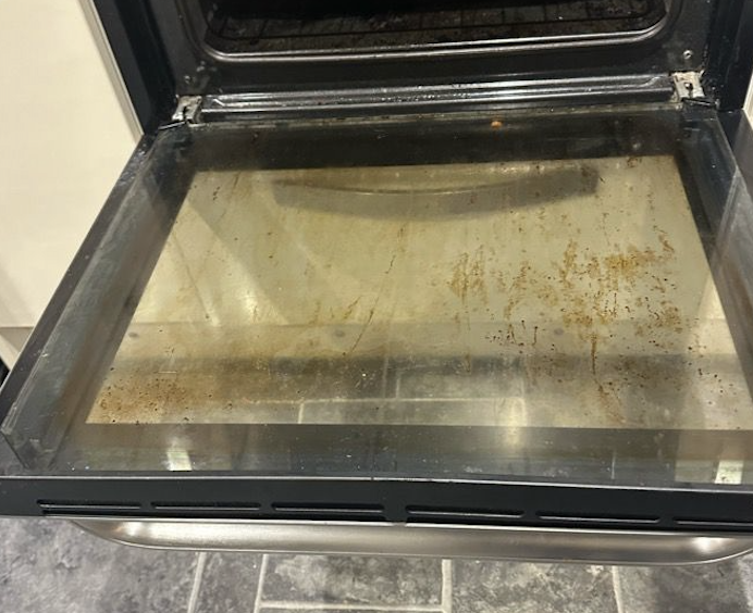 Oven door glass before cleaning - showing grease and grime