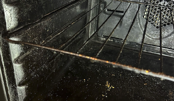 Oven interior before cleaning - greasy base and dirty racks