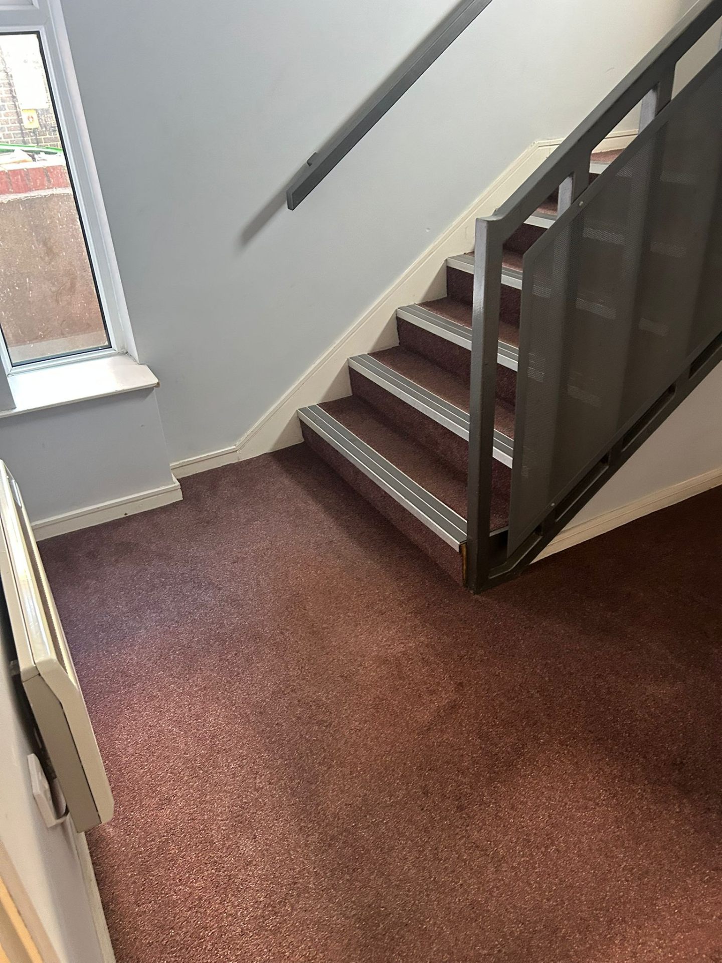 Clean stairway area with well-maintained burgundy carpeting and spotless handrails