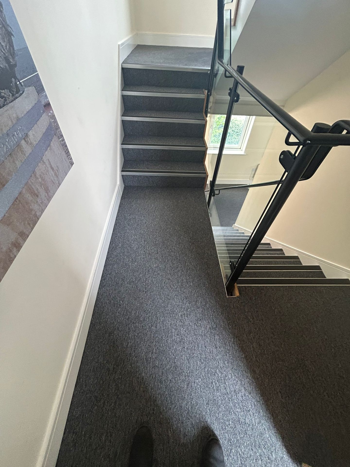 Immaculate stairwell with pristine grey carpeting and modern glass railings