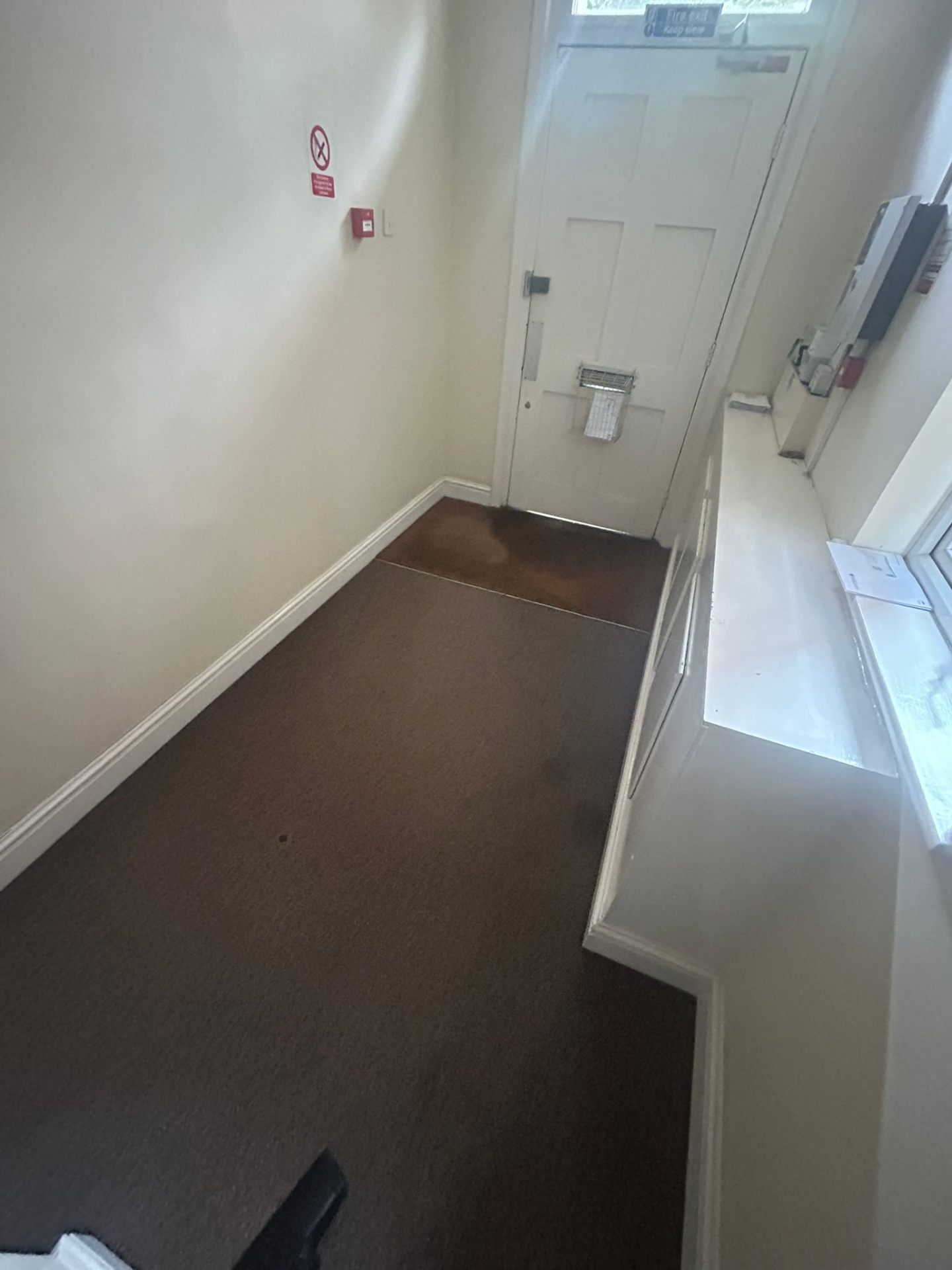 Clean communal entrance area with immaculate dark carpeting and bright white doors