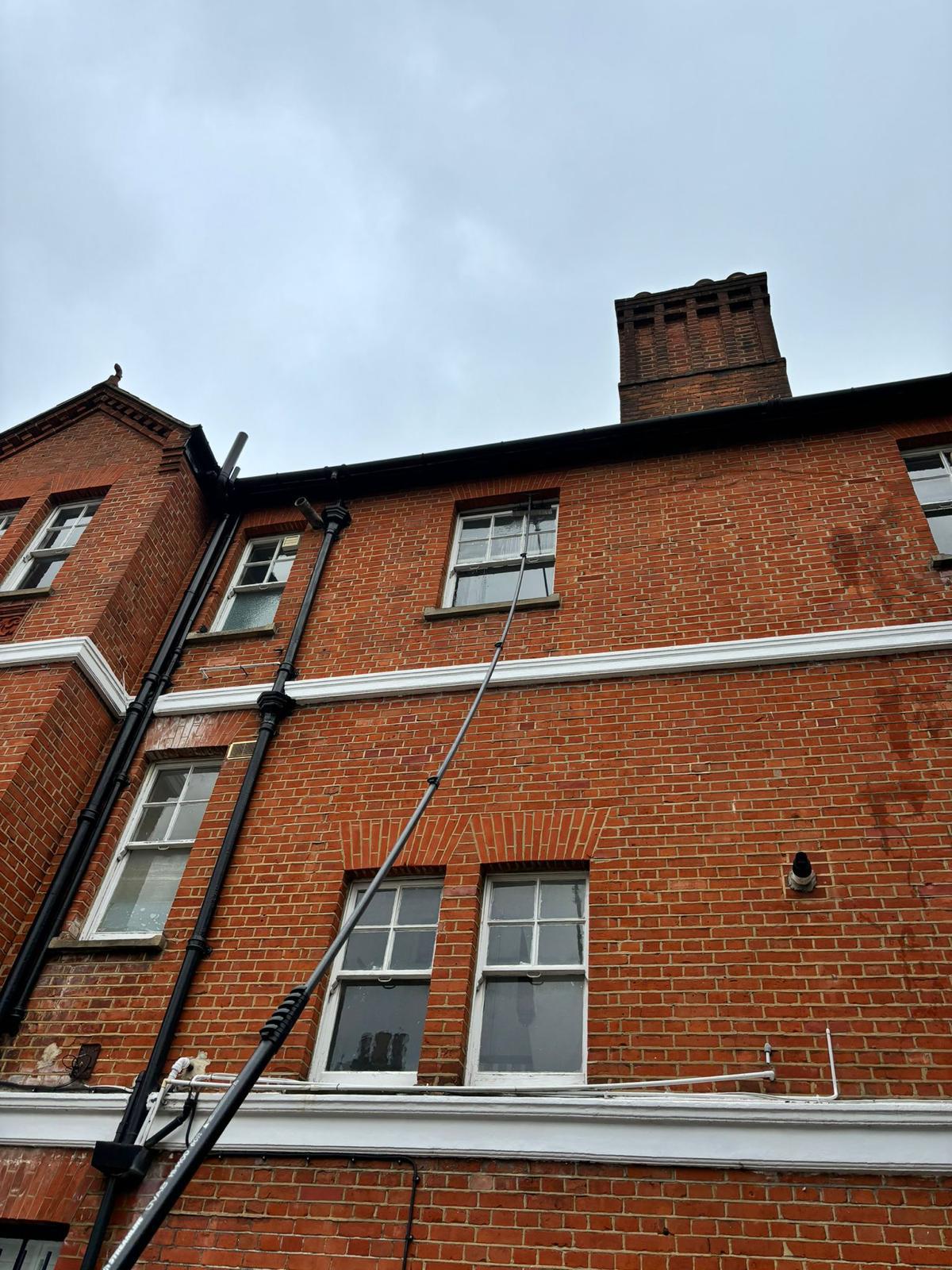 Water-fed pole system reaching high windows on multi-story brick building