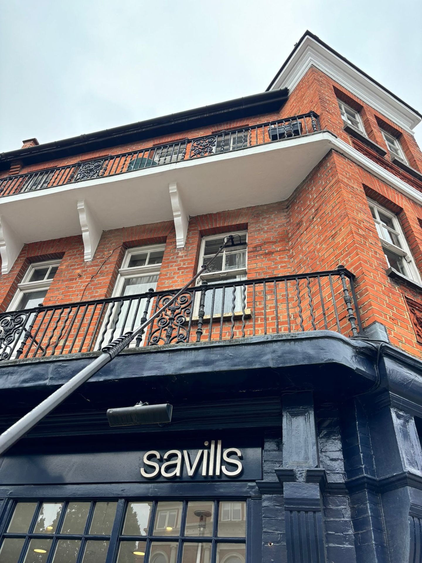 Professional window cleaning on historic brick building with water-fed pole system