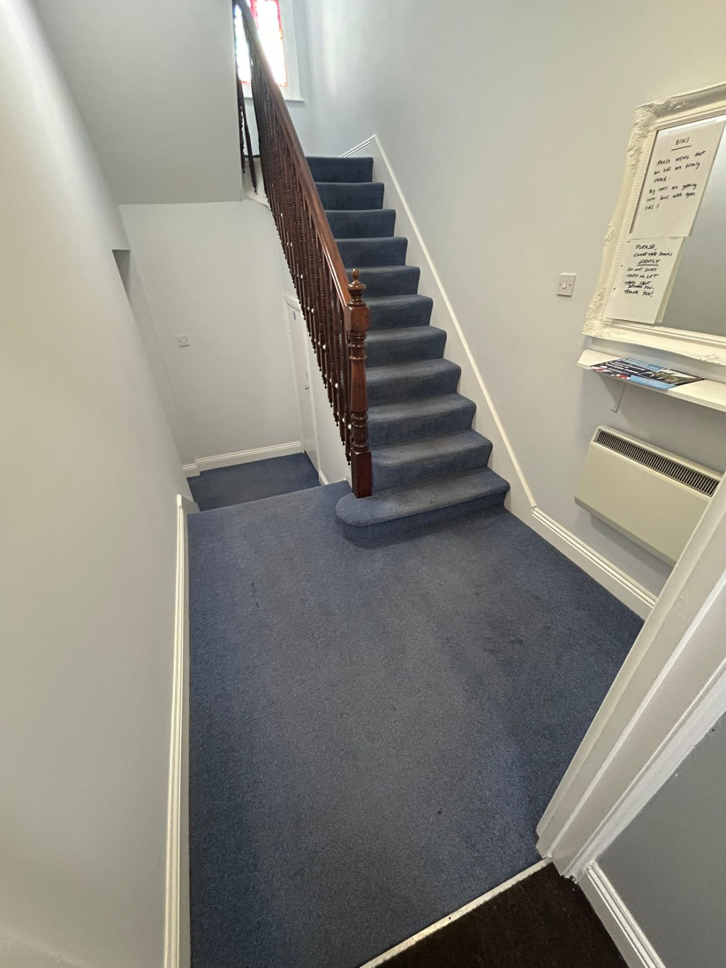 Professionally maintained stairway with clean blue carpeting and polished wooden handrails
