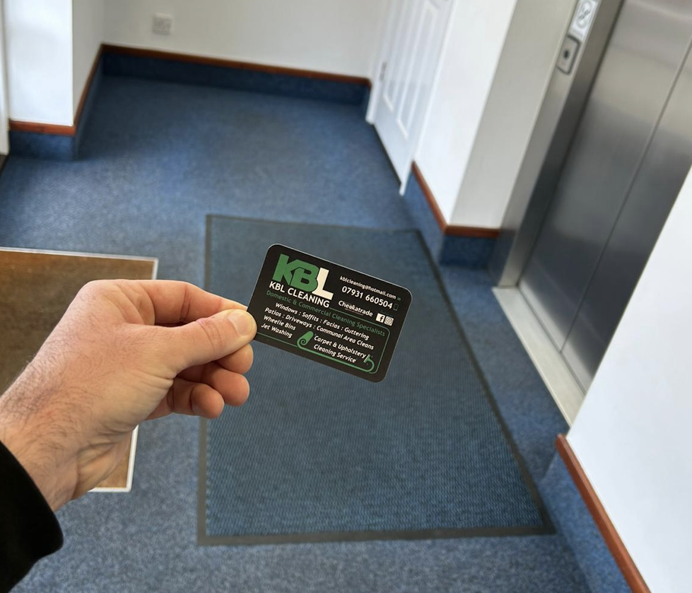 KBL Cleaning business card displayed in professional communal area with clean blue carpet and elevator access