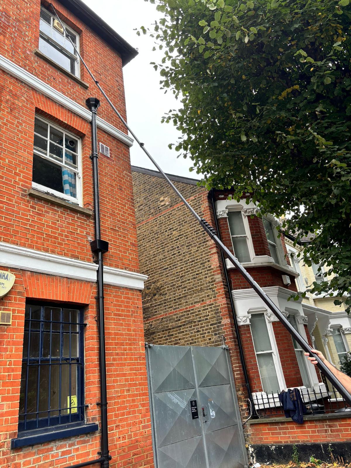 Professional window cleaning on residential brick building using water-fed pole system